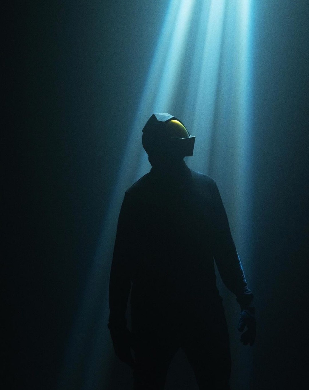 Person silhouetted in dramatic lighting wearing VR headset, looking up into beams of light in a dark indoor setting.