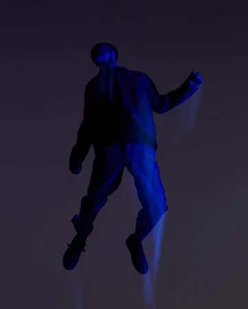 An adult poses mid-air, bathed in deep blue lighting. The individual wears dark clothing against a muted gray background, creating a surreal effect.