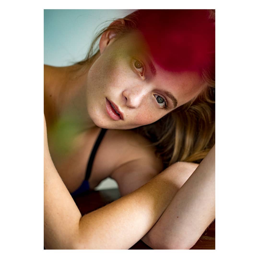 Close-up portrait of a fair-skinned adult female with freckles, blue eyes, and long blonde hair in a photo studio with diffused lighting.