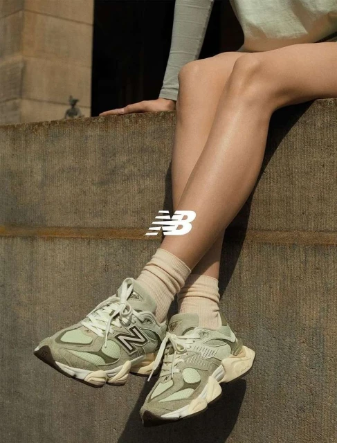 Athletic shoes: A woman sits with gray New Balance sneakers. Neutral-toned socks and background. Product, shoe, and fashion photography.