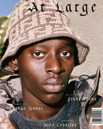 Portrait of a black man wearing a patterned knit bucket hat and a puffer jacket, photographed by Magnus Unnar.