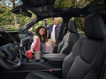 Interior view of a modern luxury car with a man and young girl entering, dark leather seats, and panoramic glass roof.