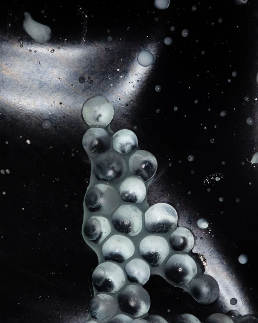 Abstract image featuring clusters of translucent spheres against a dark, textured backdrop with scattered highlights and reflections.