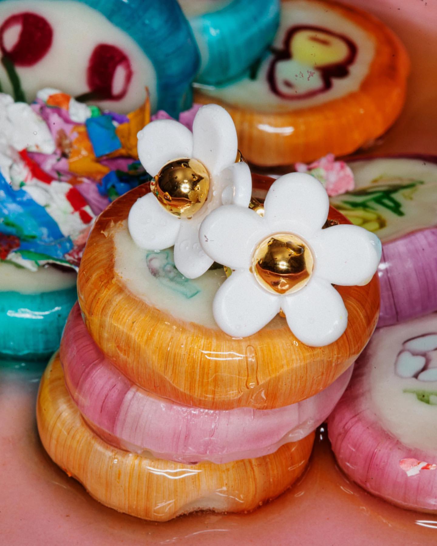 Close-up of stack of colorful, round lollipops, decorated with flower-shaped candies, creating a whimsical and vibrant dessert still life.