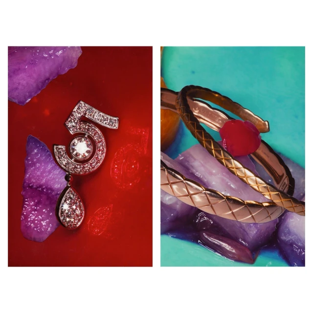 Still life of diamond '5' brooch and gold bracelets on textured surfaces. Jewelry photography with contrasting red and turquoise backgrounds.