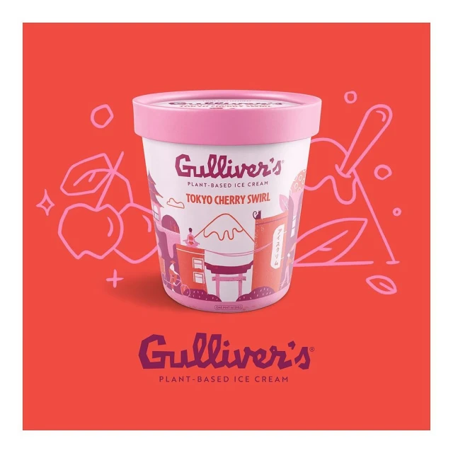 Close-up of a container of plant-based ice cream by Gulliver's, featuring a Tokyo Cherry Swirl flavor, set on a coral-colored surface.