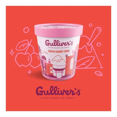 Close-up of a container of plant-based ice cream by Gulliver's, featuring a Tokyo Cherry Swirl flavor, set on a coral-colored surface.