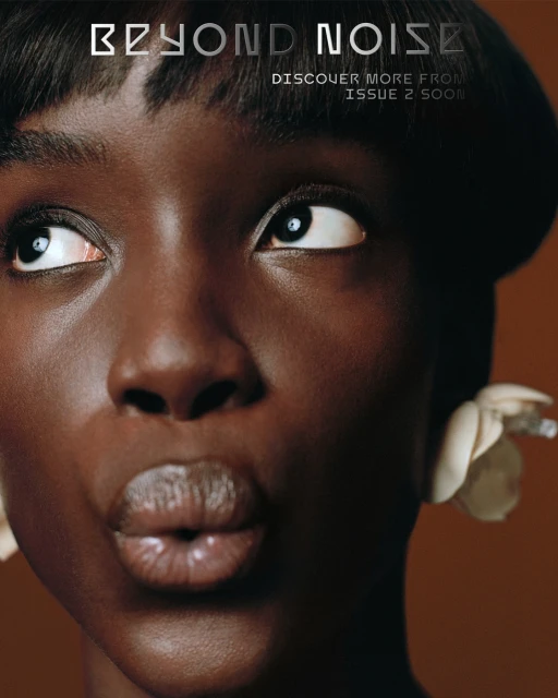 Close-up portrait of a dark-skinned adult female model with short black hair, wearing floral earrings, and looking upwards on a brown background.