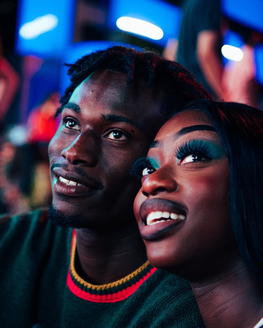 Close-up of an African American couple smiling and looking upwards, captured in a softly lit indoor setting with a focus on their faces.