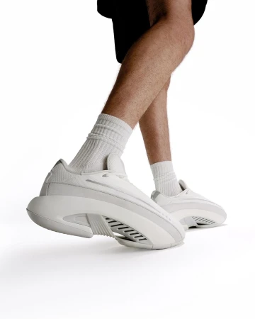 Close-up of a person wearing white sneakers and ribbed socks against a clean white background
