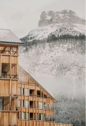 Modern wooden architecture building exterior against a snowy mountain landscape under an overcast sky
