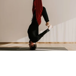 Man upside down practicing aerial yoga in a hammock with wooden flooring and natural light.