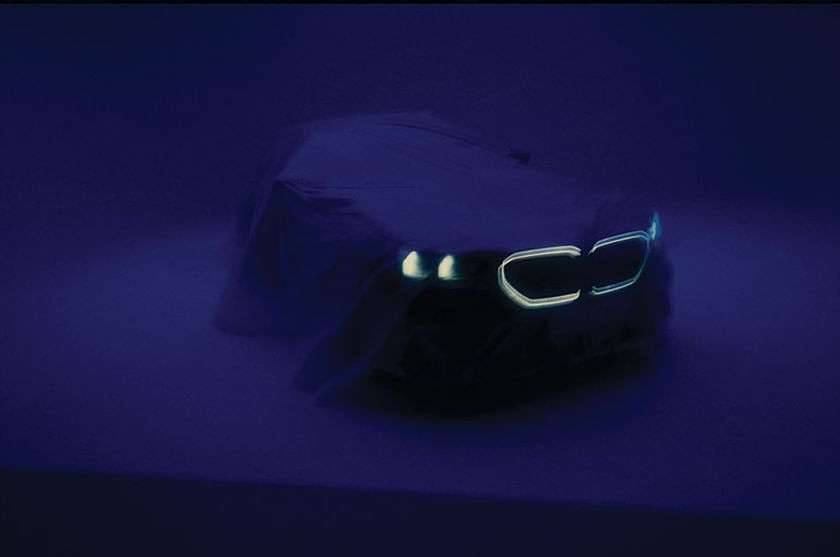A shrouded car with illuminated lights is prominently displayed against a dark blue background, creating a mysterious and captivating image.