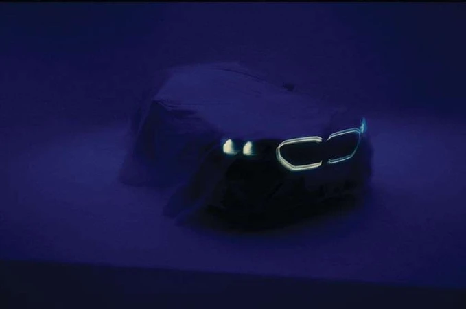 A shrouded car with illuminated lights is prominently displayed against a dark blue background, creating a mysterious and captivating image.