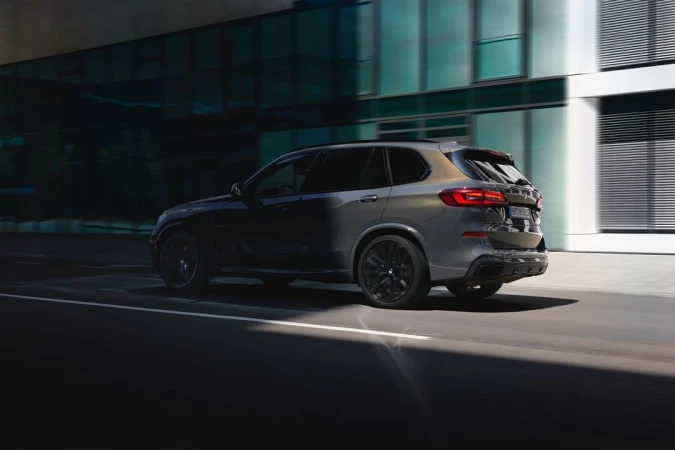 Grey luxury SUV driving along a city street past modern glass architecture