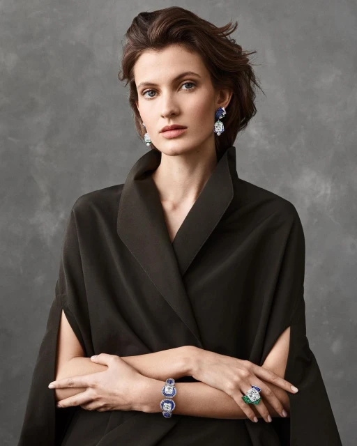 Portrait of a brunette woman wearing a formal black dress and fine jewelry, including earrings, a bracelet, and a ring.