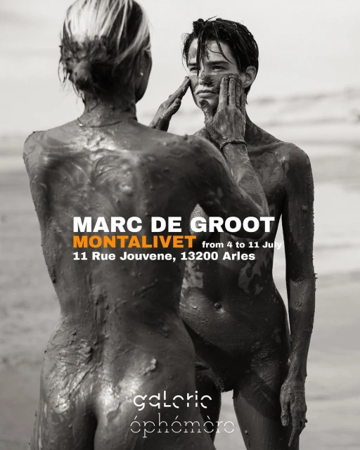 Two nude figures covered in mud pose on a beach in this high-contrast black and white promotional image for an art exhibition.