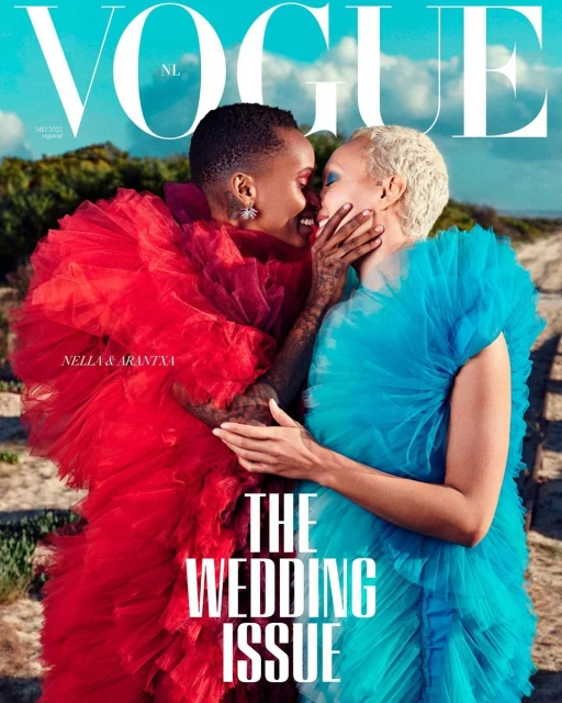 Vogue cover featuring two women in ruffled dresses embracing on a sandy path with beach grass and an overcast sky in the background.