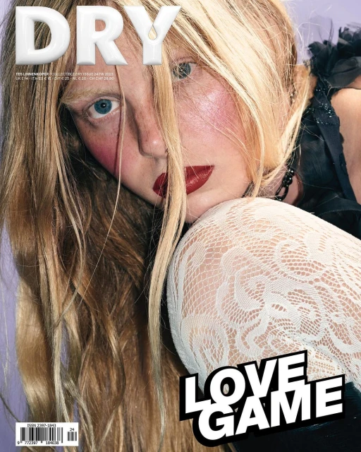 Magazine cover featuring a fair-skinned young adult female with long blonde hair, red lipstick, and white lace stockings on a purple background.
