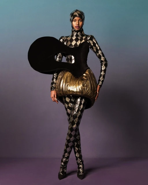 Full-length shot of a fashion model in a futuristic, harlequin-patterned costume against a blue and purple gradient background.