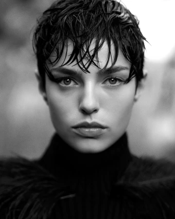 Close-up monochrome portrait of a woman with short wet-look hair and dark eyeliner wearing a black high-collar garment