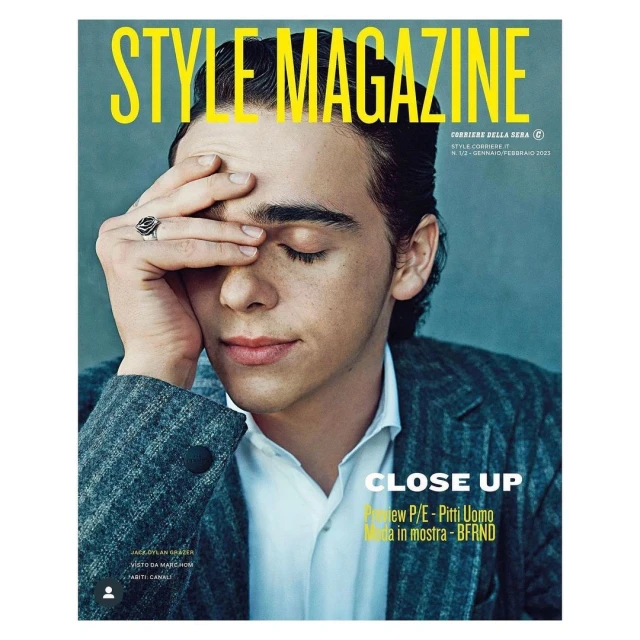 Magazine cover featuring a close-up of a young adult male with his hand on his forehead, wearing a suit, and jewelry on his finger.