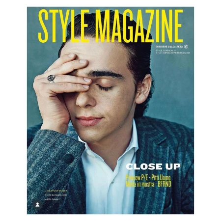 Magazine cover featuring a close-up of a young adult male with his hand on his forehead, wearing a suit, and jewelry on his finger.