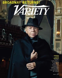 Portrait of Andrew Lloyd Webber wearing a black coat and fedora inside a theatre by photographer Marc Hom
