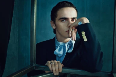 Portrait of young man with dark hair wearing black blazer and striped shirt with bow by Marc Hom