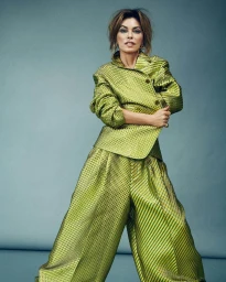 Shania Twain wearing a structured metallic chartreuse quilted jacket and matching wide-leg trousers against a solid grey background