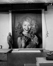 Behind-the-scenes monochrome photo of a large portrait print featuring Gwyneth Paltrow with a snake around her neck.