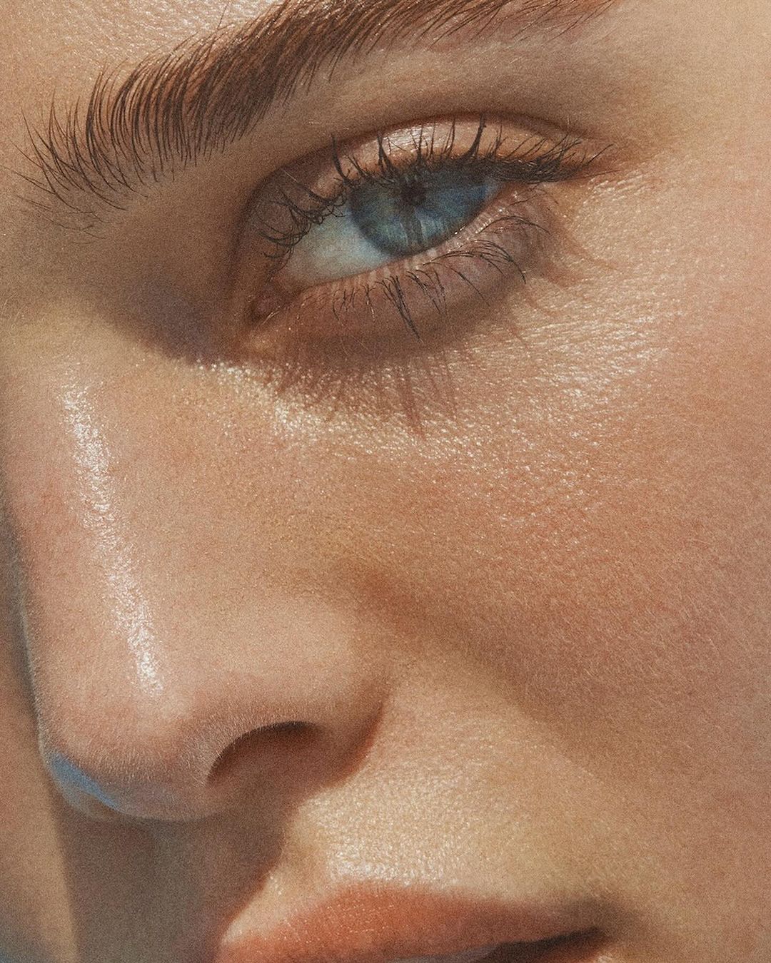 Close-up macro shot of a woman eye and cheek with natural skin texture and warm golden lighting by Marc Philbert