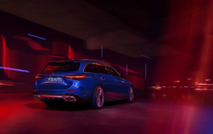 Rear view of a blue Mercedes-Benz C43 AMG wagon in motion, showcasing sleek design, quad exhausts, and red and blue lighting.
