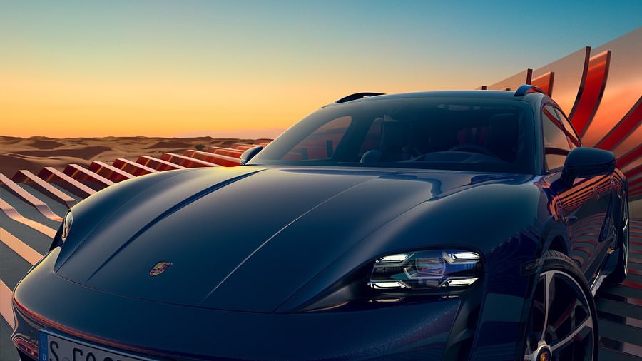 Sleek dark blue Porsche Taycan Cross Turismo electric vehicle parked against a desert sunset and abstract, geometric background.