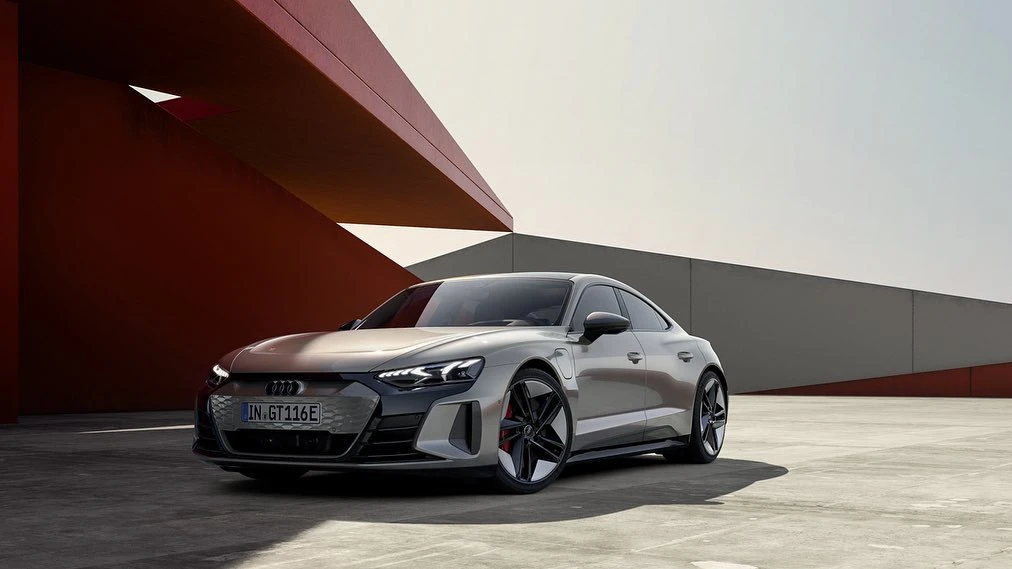 Sleek silver Audi e-tron GT electric car showcased against modern architecture backdrop, emphasizing automotive design and innovation.