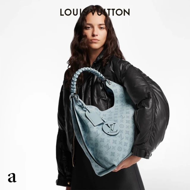 Fashion shot featuring a young adult woman wearing a black jacket and holding a Louis Vuitton light blue handbag with monogram print.