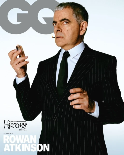 Magazine cover featuring Rowan Atkinson in a pinstripe suit, holding a lighter, with the 'GQ' logo and text about a heroes special.