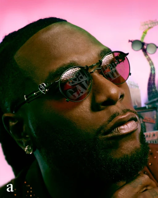 Close-up of adult male wearing sunglasses with reflected text in an urban-style setting with a pink gradient background.