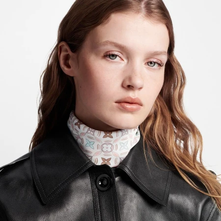 Portrait of a female model wearing a black leather jacket and a patterned silk neck scarf against a white background