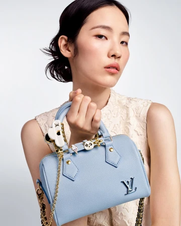 East Asian woman holding a powder blue leather handbag against a plain white background
