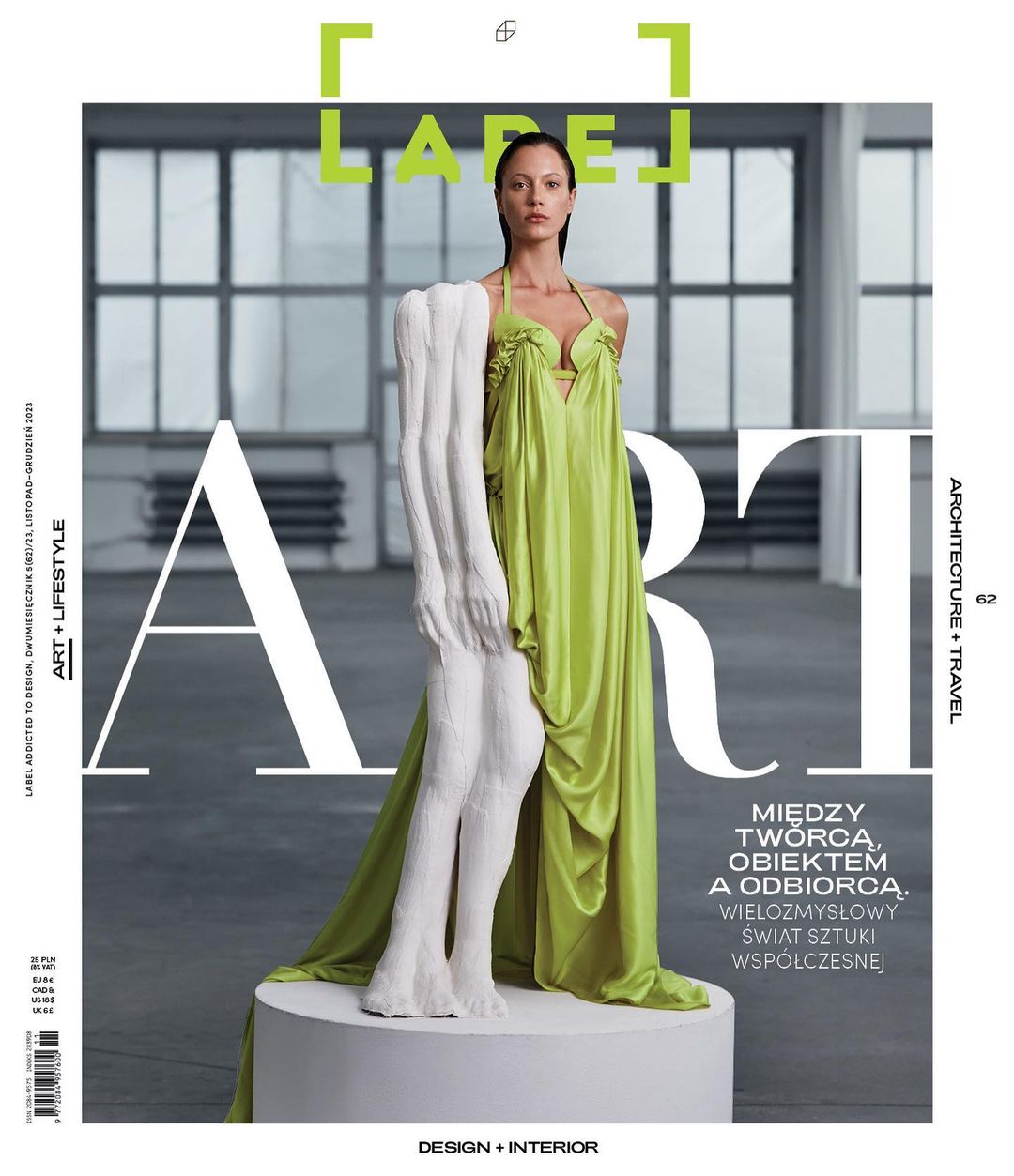Magazine cover featuring a woman in a green dress posing with a sculpture in a minimalist indoor setting with natural lighting.