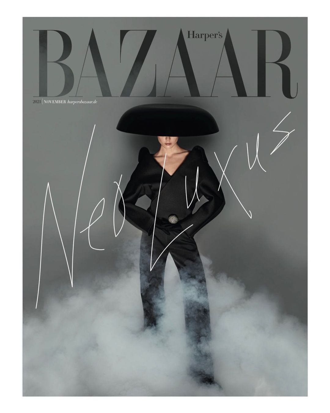 Fashion editorial cover of Harper's Bazaar featuring a woman in a dark couture outfit with a mushroom-shaped headpiece surrounded by fog.