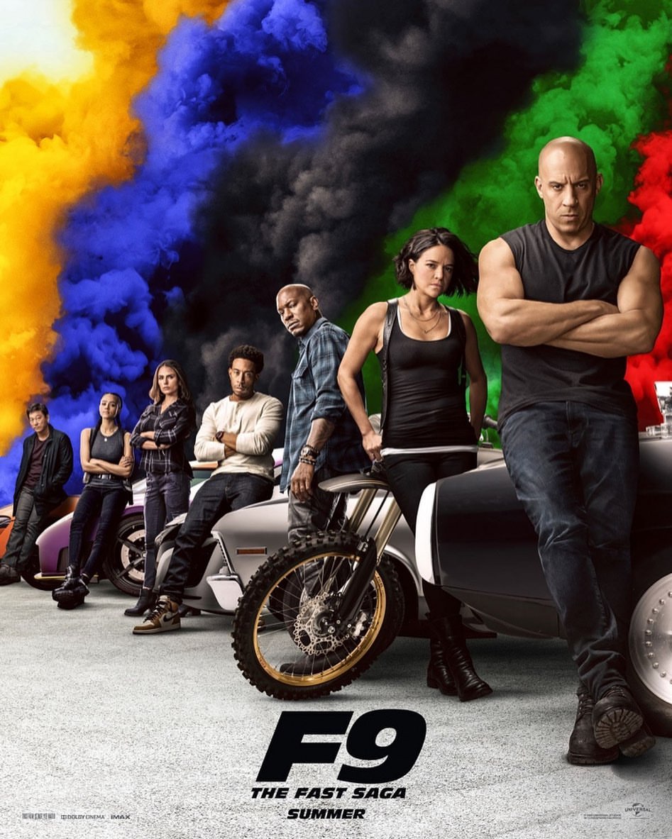 Movie poster for F9: The Fast Saga featuring Vin Diesel and the cast, with motorcycles and cars, against a backdrop of colorful smoke.