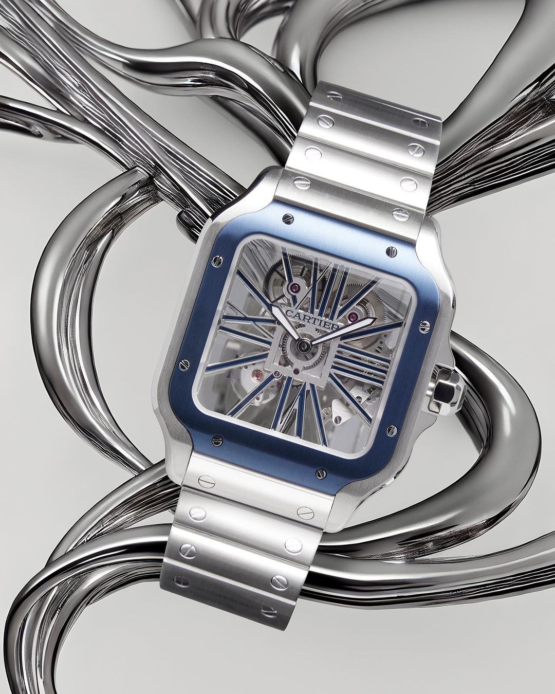 Elegant Santos de Cartier wristwatch with a stainless steel case, skeleton dial, and blue accents, showcased against a stylized metallic background.