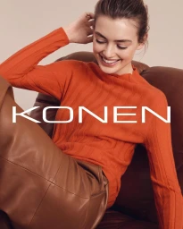 Smiling woman in an orange ribbed sweater seated on a brown leather armchair, photographed by Marcus Gaab