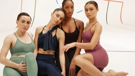 Four female models wearing athletic sports bras and leggings posing together against a white studio background.