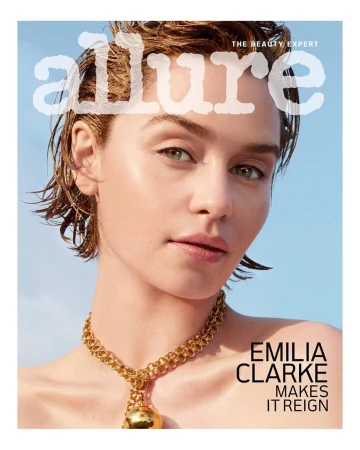 Close-up portrait of Emilia Clarke with wet-look short hair wearing a gold chain necklace against a clear blue sky