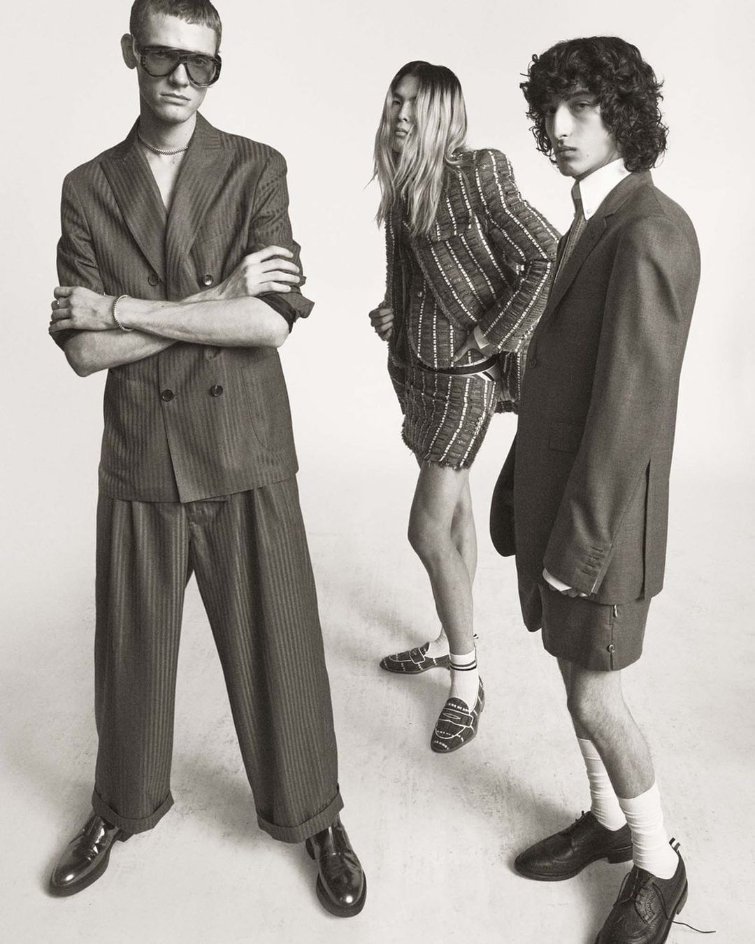 Three fashion models pose in striped suits in a studio, showcasing contemporary style and design against a neutral backdrop.
