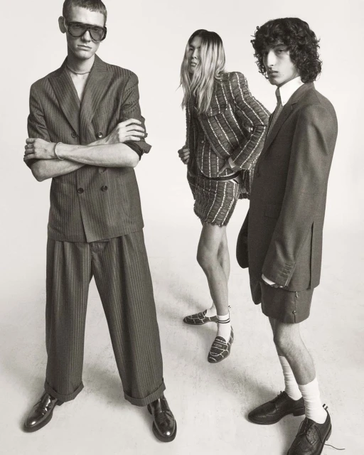 Three fashion models pose in striped suits in a studio, showcasing contemporary style and design against a neutral backdrop.