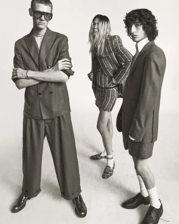 Three fashion models pose in striped suits in a studio, showcasing contemporary style and design against a neutral backdrop.